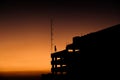 a silhouette of a building against a sunset background, a beautiful orange-yellow sky. Royalty Free Stock Photo