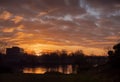 Silhouette of a building surrounded by trees at sunset, Warm glowing cloudy sky Royalty Free Stock Photo