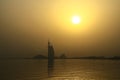 The silhouette of the Burj Al Arab hotel in the morning, and the buildings above the sea, ocean, over which the sun rises