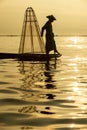 Silhouette Burmese fishermen wearing traditional clothes standing at the back of the boat, preparing morning fishing equipment at