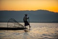 Silhouette of a burmese man wearing a hat Use the rowing legs to catch fish in the evening