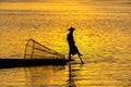 Silhouette of a Burmese man wearing a hat, using paddle legs to catch fish in the evening Royalty Free Stock Photo