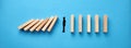 Silhouette of a businessman in apathy or inertia against collapsing wooden dominos on blue background. Business crisis and