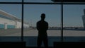 Silhouette of a businessman back overlooking the parking space behind the window. HDR. Rear view of a young man standing Royalty Free Stock Photo