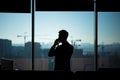 Silhouette of a businessman man in a modern office on the background of the window, a man talking on the phone Royalty Free Stock Photo