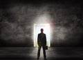 Silhouette of businessman standing in front of a light door way to success. Business professional looking to a bright