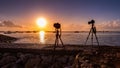 Silhouette of camera on tripod shooting sea with sunset