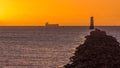 Silhouette of cargo ship at golden hour with lighthouse on Bull Island Royalty Free Stock Photo