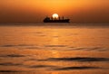 Silhouette of cargo ship with sunset on ocean horizon Royalty Free Stock Photo