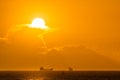 Silhouette of cargo ships on far distance at golden hour with solar disc Royalty Free Stock Photo