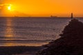 Silhouette of cargo ships. Solar disc, shines from behind cloud. Lighthouse on Bull Island Royalty Free Stock Photo