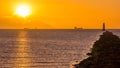 Silhouette of cargo ships. Solar disc, shines from behind cloud. Lighthouse on Bull Island Royalty Free Stock Photo