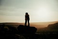 Silhouette caucasian husband and wive hugging on top of mountain at sunset while on honeymoon