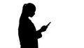 Silhouette Cheerful cute young woman doctor typing text on phone while walking. Royalty Free Stock Photo