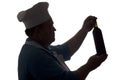 Silhouette of a chef looking at a bottle of wine and thinking on a white isolated background, profile of a male face in a cook hat