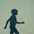 Silhouette of a child captured in profile on a textured green wall. The shadow depicts a Royalty Free Stock Photo