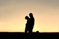 Silhouette of Child Laughing and Hugging Father at Sunset