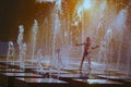 Silhouette of a child playing with a spray of a fountain on a hot summer day. Royalty Free Stock Photo