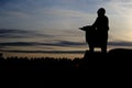 Silhouette of a child standing against the background of the evening sky over a dark forest at sunset. Royalty Free Stock Photo