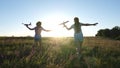 Silhouette of children playing on an airplane on a flower field. Dreams of flying. Happy childhood. Two girls play with Royalty Free Stock Photo