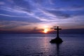 Silhouette of Christian cross on the stone thumb in the lake against a bluish sunset sky Royalty Free Stock Photo