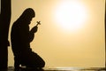 Silhouette of christian Man holding a cross cross in hands praying for blessing from god on sunlight background, hope concept Royalty Free Stock Photo