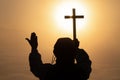 Silhouette of christian Man holding a cross, cross in hands praying for blessing from god on sunlight background, hope concept Royalty Free Stock Photo