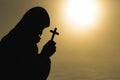 Silhouette of christian young man praying with a cross at sunrise, Christian Religion concept background Royalty Free Stock Photo