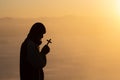 Silhouette of christian young man praying with a  cross at sunrise, Christian Religion concept background Royalty Free Stock Photo