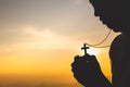 Silhouette of christian young woman praying with a  cross at sunrise, Christian Religion concept background Royalty Free Stock Photo