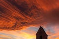 Silhouette of a church steeple under a cloudy orange sky at sunset Royalty Free Stock Photo