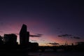 Silhouette of city buildings along the River Thames against a pink, dusk sky in London