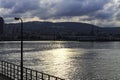 Silhouette of the city on the sea coast view from the sea with a lamppost in the foreground on the Autumn sunset. Royalty Free Stock Photo