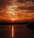 Silhouette of the city and the smoky factories and lake on background of dramatic sky at sunset bright sun and clouds