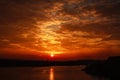 Silhouette of the city and the smoky factories and lake on background of dramatic sky at sunset bright sun and clouds Royalty Free Stock Photo