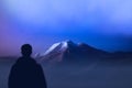 Silhouette climber stands at foot mountains watching of mountain top. expedition to Himalayas