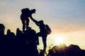 Silhouette climbing buddies help each other climb up the mountain at sunrise as the right lifestyle idea