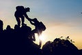 Silhouette climbing buddies help each other climb up the mountain at sunrise as the right lifestyle idea