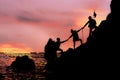 Silhouette of climbing team helping each by hand pull while climb mountain rock cliff Royalty Free Stock Photo