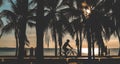 Silhouette of coconut tree and people Cyclist on the beach with sunset time. Royalty Free Stock Photo