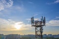 Silhouette communication tower mobile operator's antenna against the background city blocks and the evening blue sky. Royalty Free Stock Photo