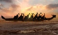 Silhouette of competitive people rowing dragon boat at sunset