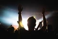 Silhouette of a concert crowd. The audience applauds the musicians on stage. The bright spotlight and dancing people