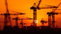 Silhouette construction cranes against backdrop of orange sunset, Generative AI Royalty Free Stock Photo