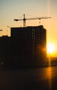 Silhouette of construction cranes over new residential buildings at sunset. Urban background Royalty Free Stock Photo
