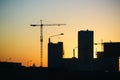 Silhouette of construction cranes over new residential buildings at sunset. Urban background Royalty Free Stock Photo