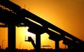 A silhouette of a construction site of monorail projects with crane, columns and tracks that is under construction at the sunset Royalty Free Stock Photo