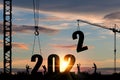 Silhouette of construction worker with crane and cloudy sky for preparation of welcome 2022 new year party and change new business