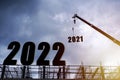 Silhouette of construction worker with crane and cloudy sky for preparation of welcome 2022