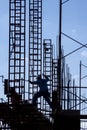 Silhouette of construction worker jumping accross scaffolding among steel framing